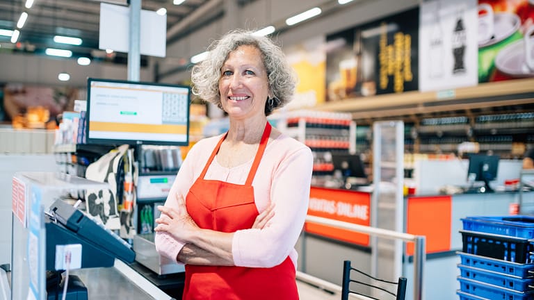 a smiling person in an apron at a register gettyimages .jpg