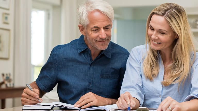 mature couple discussing finances with pens and paper.jpg