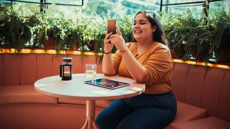 person at coffee shop table with phone JvOTB.width .jpg