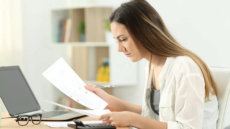 woman typing on calculator while looking at d.width qNdigi.jpg