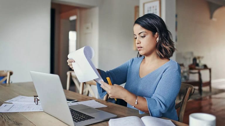 woman with bills and laptop in kitchen EEKd.width .jpg