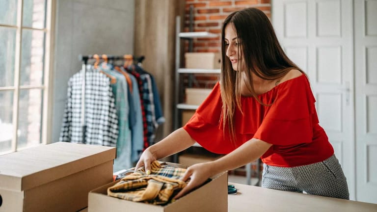 Woman boxing up some of her clothes. yDycw.width .jpg