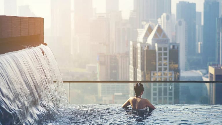 Woman in rooftop pool over city EEPugl.width .jpg