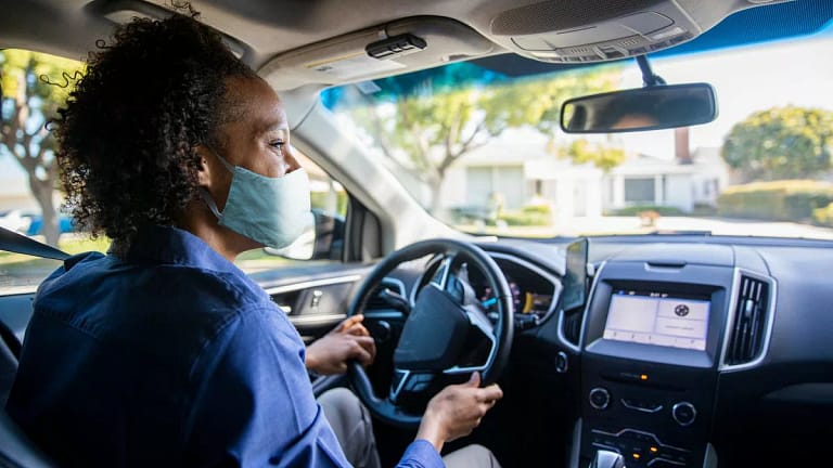 Woman wearing face mask driving her car and s.width HlXYHag.jpg