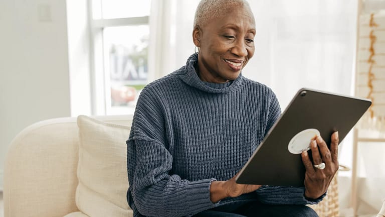 older person sitting on a couch looking at a tablet.jpg
