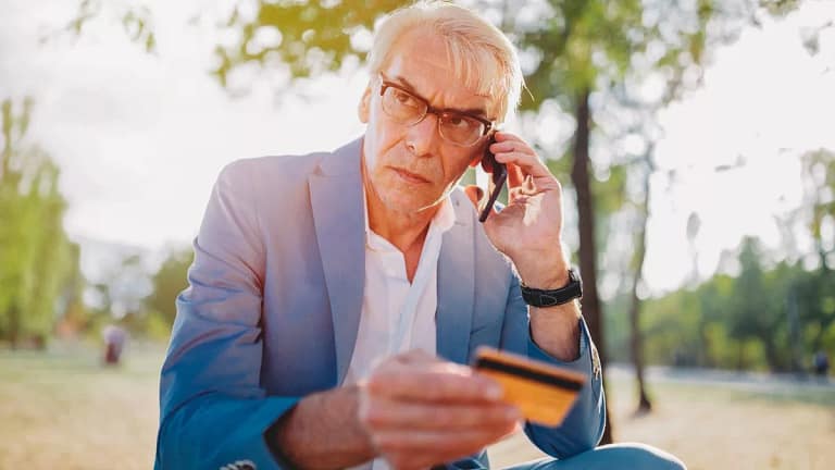 older man upset on phone holding credit card .width NRkzbw.jpg