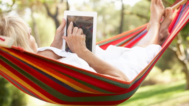senior woman relaxing in hammock reading ebook.jpg