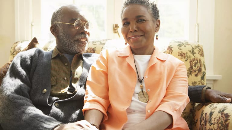 two older people sitting on a couch holding hands.jpg