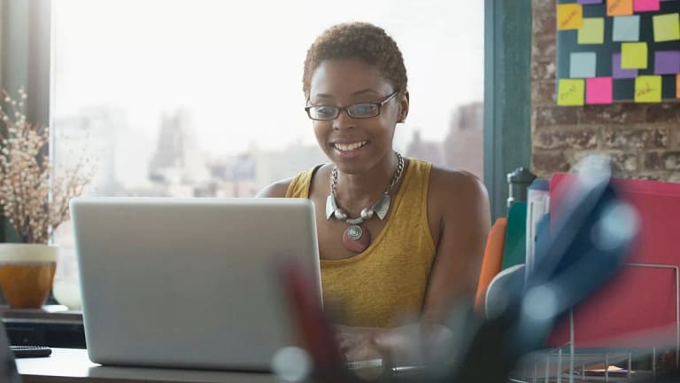 Woman smiling as she uses her laptop yKHtHfd.width .jpg
