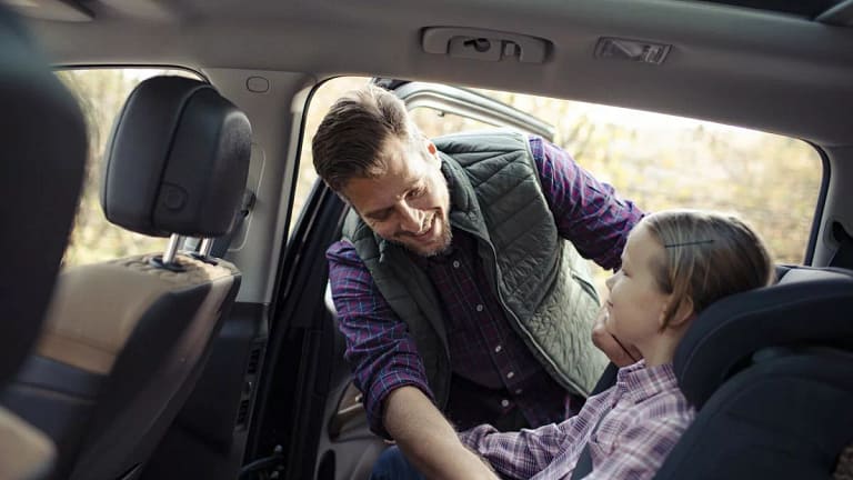 dad helping young daughter into car seat DYLl.width .jpg