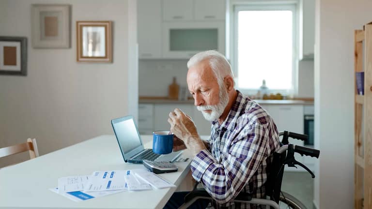 man in wheelchair at desk with financial stuff.jpg