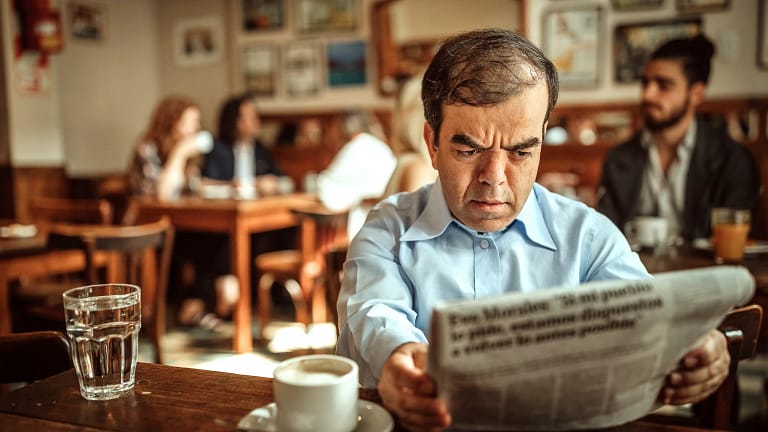 man with dwarfism reading newspaper at cafe.jpg