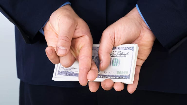 money behind back fingers crossed corporate tax getty.jpg