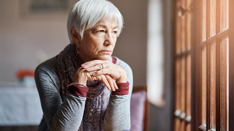 older person sitting at a table looking out a window.jpg