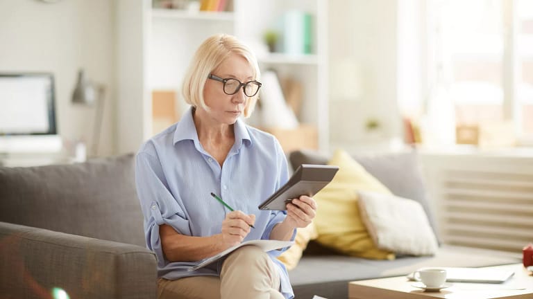 older woman sitting on a couch looking at a calculator.jpg