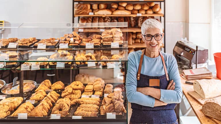 senior woman working a smiling person wearing an apron in a bakery gettyimages .jpg