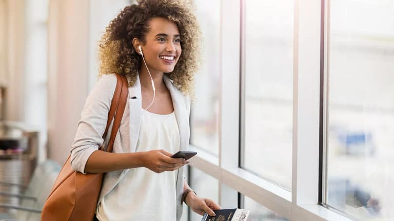 woman smiling in airport with suitcase and pa.width zsxbQ.jpg