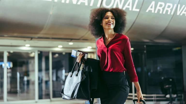 Smiling traveler walks through airport with l.width .jpg