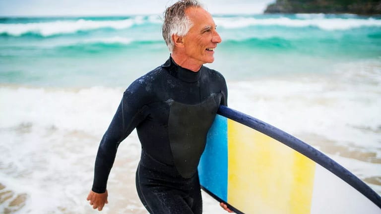 Person in wet suit carrying surf board in fro.width .jpg