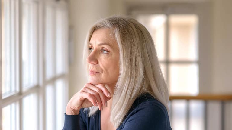 older person with serious expression looking out a window.jpg
