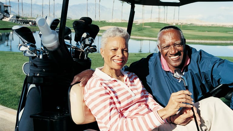 senior man and woman sitting in golf cart smiling poc.jpg