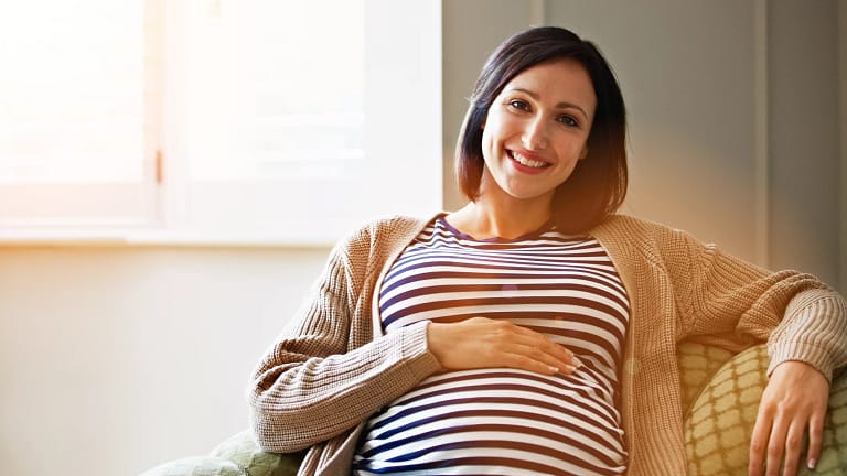 getty pregnant happy smiling on couch.jpg
