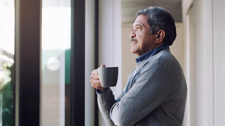 older person holding a mug and looking out a window.jpg