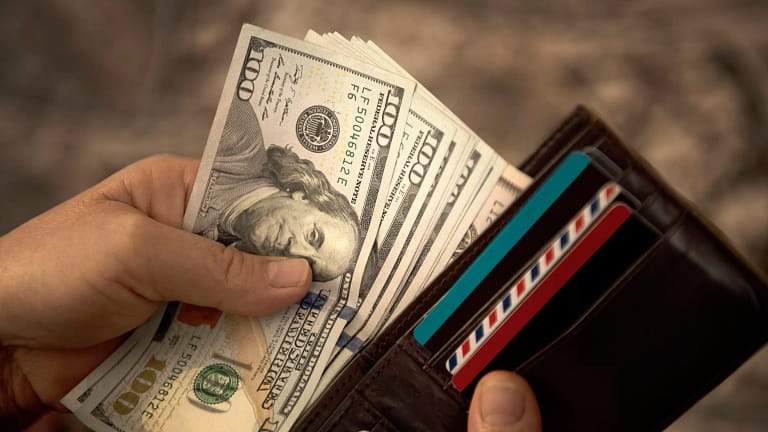 person placing hundred dollar bills into a wallet.jpg