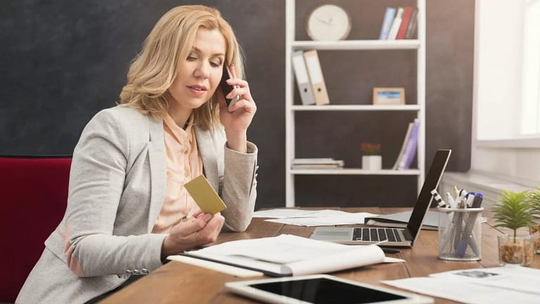 Woman holding credit card while talking on ph.width QhZCHA.jpg