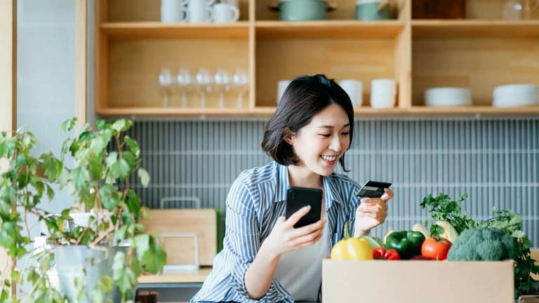 Young woman online shopping in kitchen JvCuFF.width .jpg