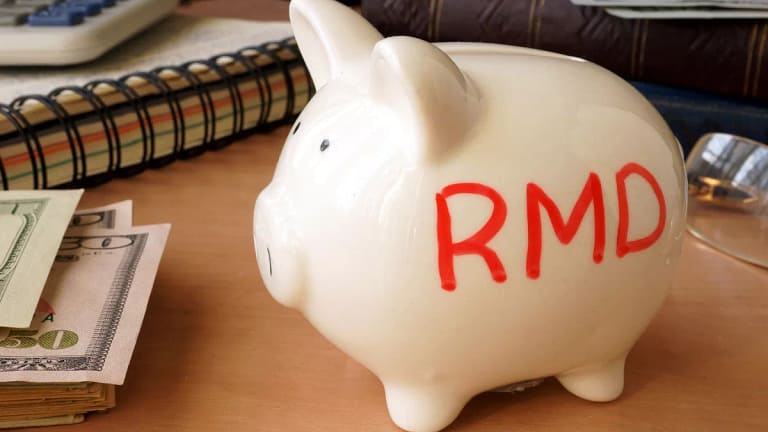 getty images piggy bank with rmd written on its side next to stack of paper money retirement savings k ira cash x bdf.jpg