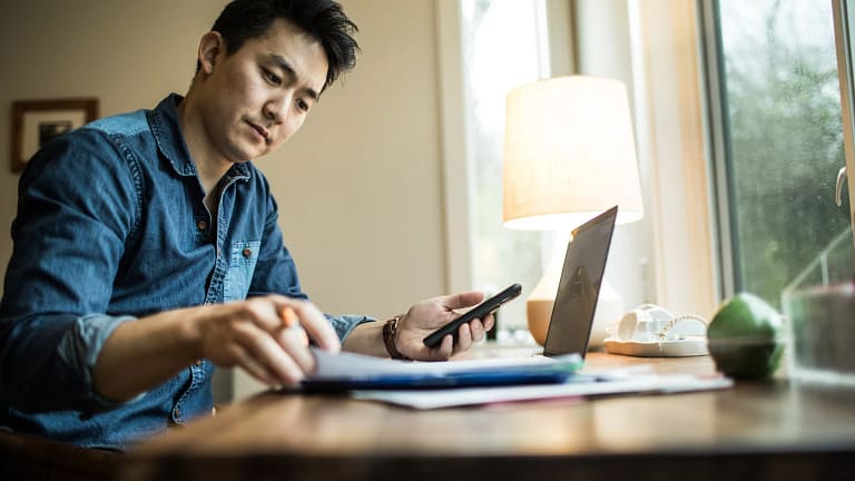 person in home office holding smartphone and looking at document.jpg