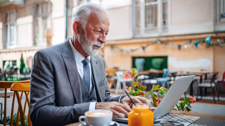 senior businessperson typing on laptop at coffee shop.jpg
