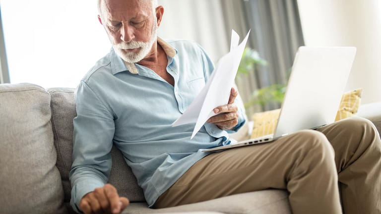 senior man couch docs calc laptop gettyimages .jpg