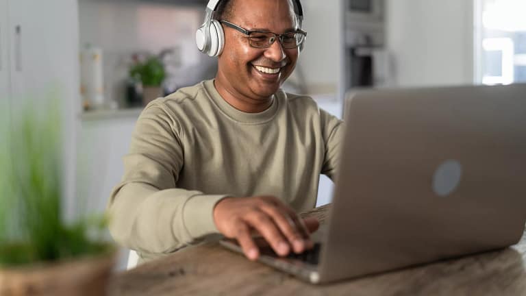 smiling person at laptop wearing headphones gettyimages .jpg