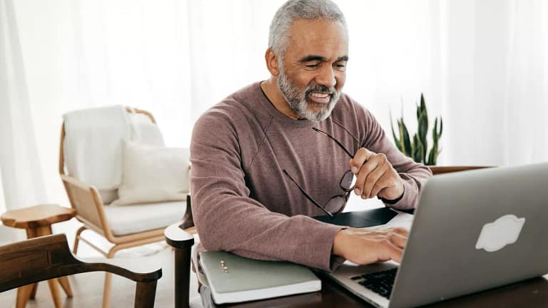 smiling person holding glasses and looking at laptop.jpg