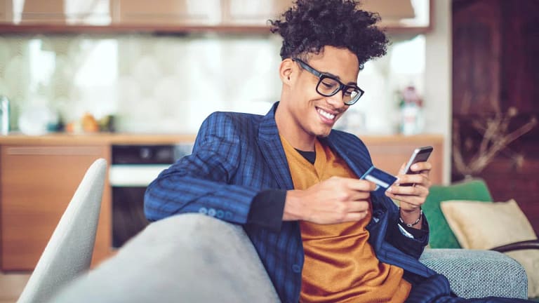 Young man smiles holding credit card XSsJhs.width .jpg