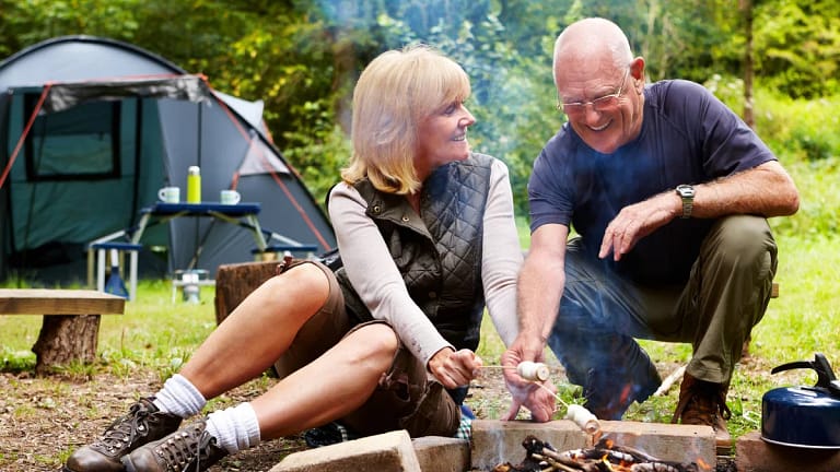 smiling couple roasting marshmallows at campsite.jpg