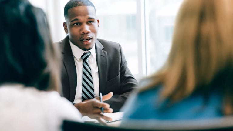 suited businessperson talking to two clients.jpg