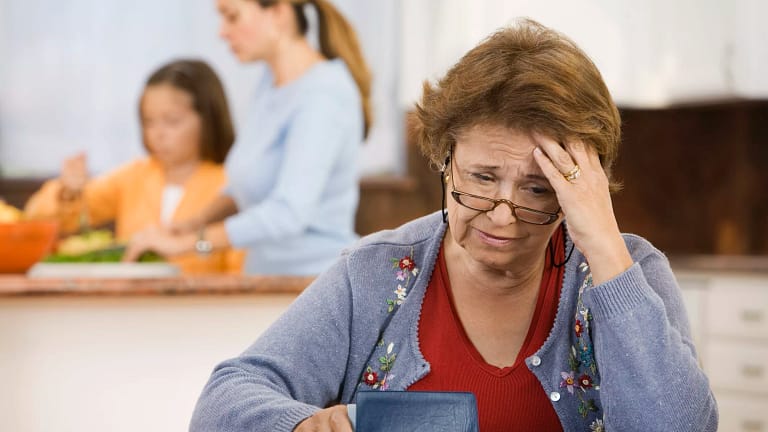 worried senior woman holding checkbook.jpg